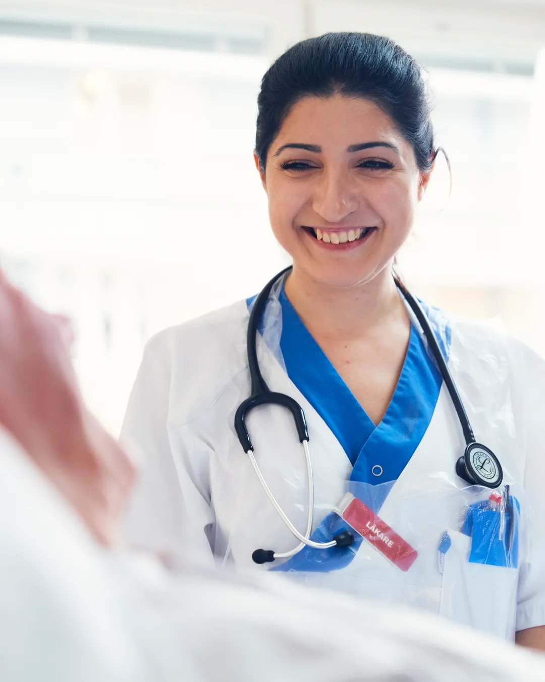 En läkare ler mot en patient som ligger i en sjukhussäng.