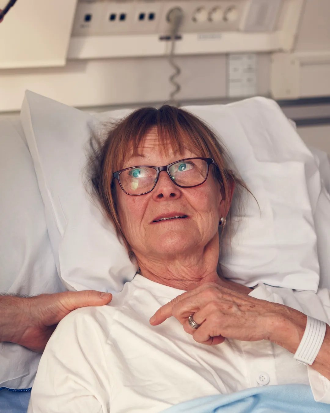 En äldre kvinna i en sjukhussäng undersöks av en läkare.
