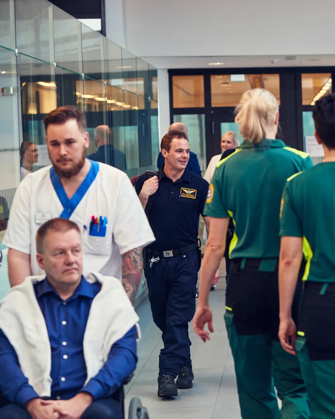 En blandning av patienter och vårdgivare som går i en sjukhuskorridor.