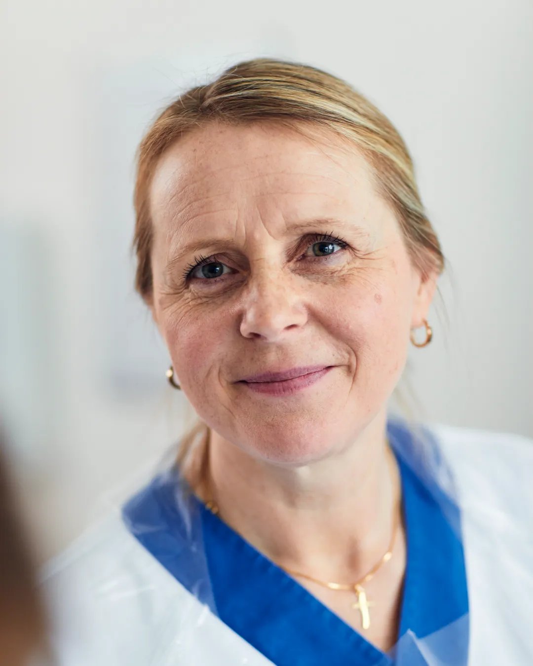 A woman in a white coat smiles at the camera.
