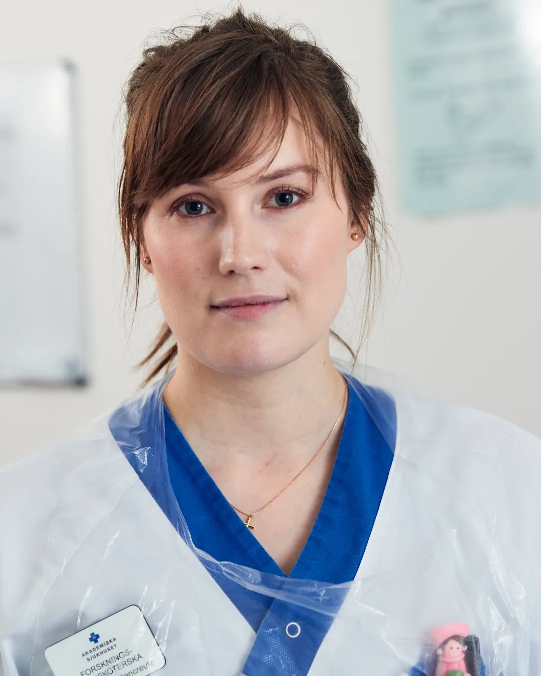 En kvinna i vit labbrock med ett blått band runt halsen.