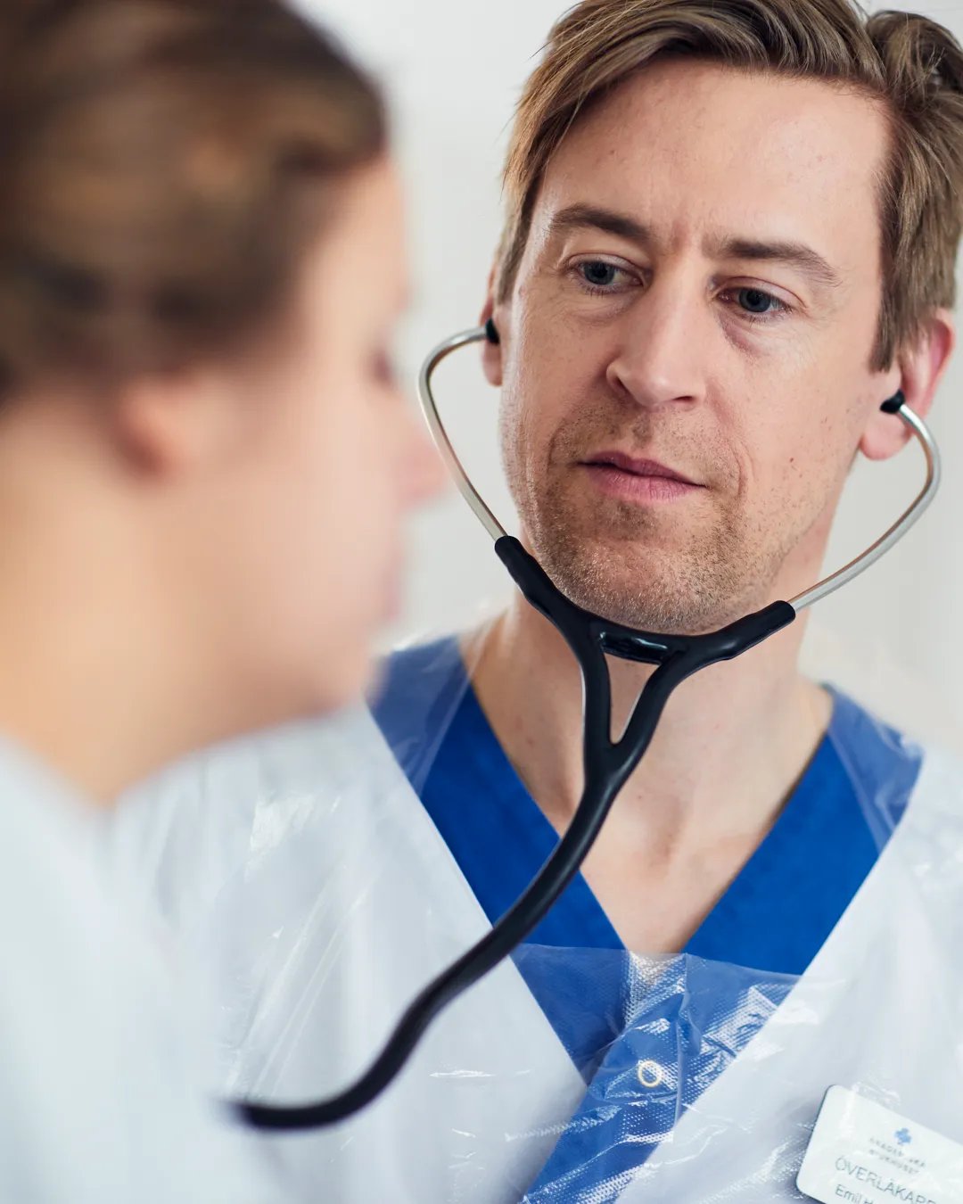 En läkare som lyssnar på en patient med ett stetoskop.