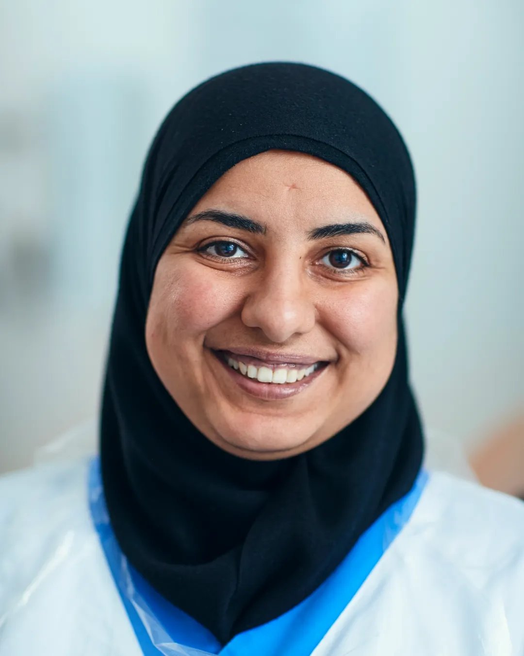 En kvinna i hijab ler mot kameran.