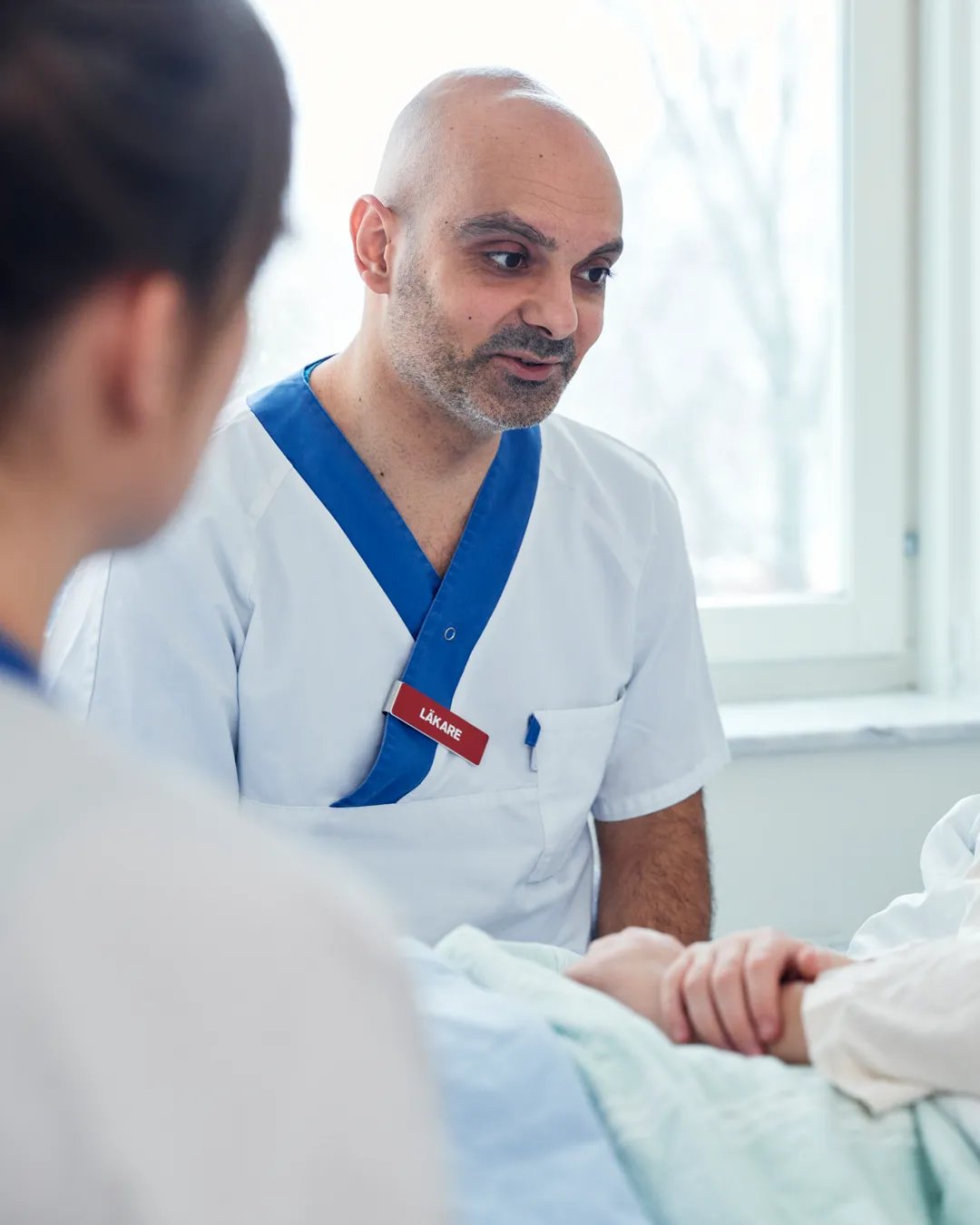En läkare pratar med en patient i en sjukhussäng.