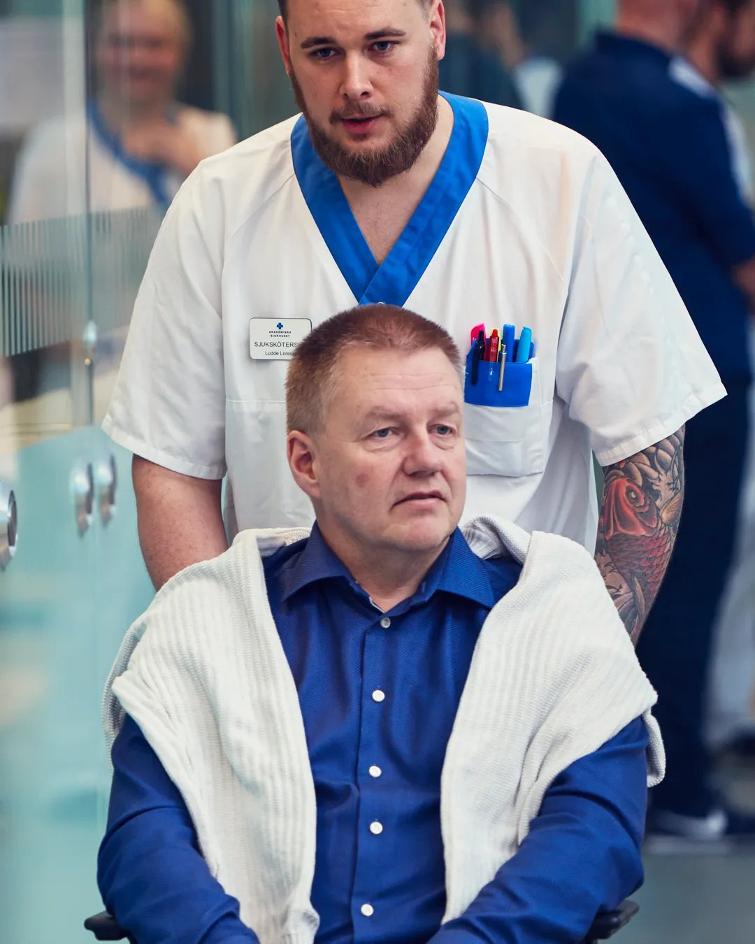 En sjuksköterska skjutsar en man i rullstol.