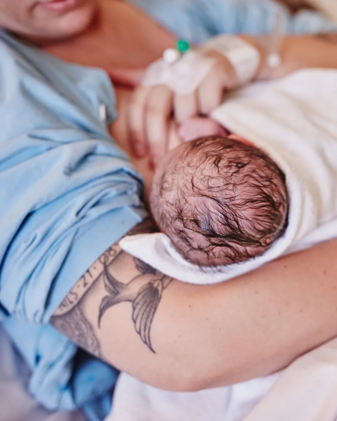 En kvinna håller en baby insvept i en filt.