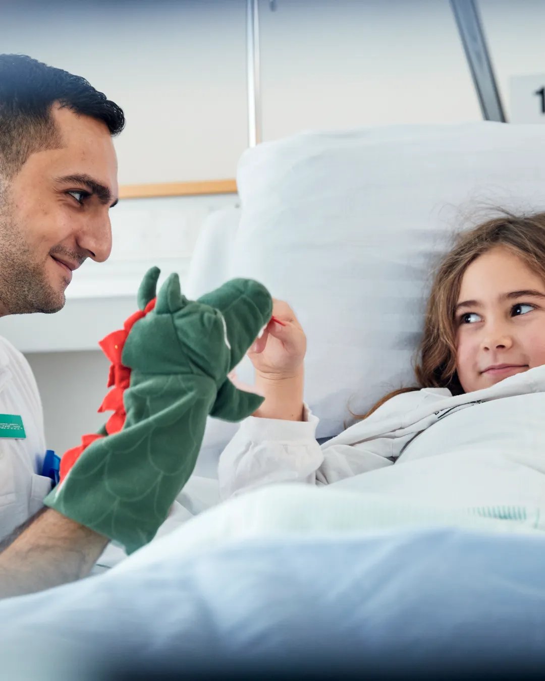 A man makes a hospitalized girl smile.