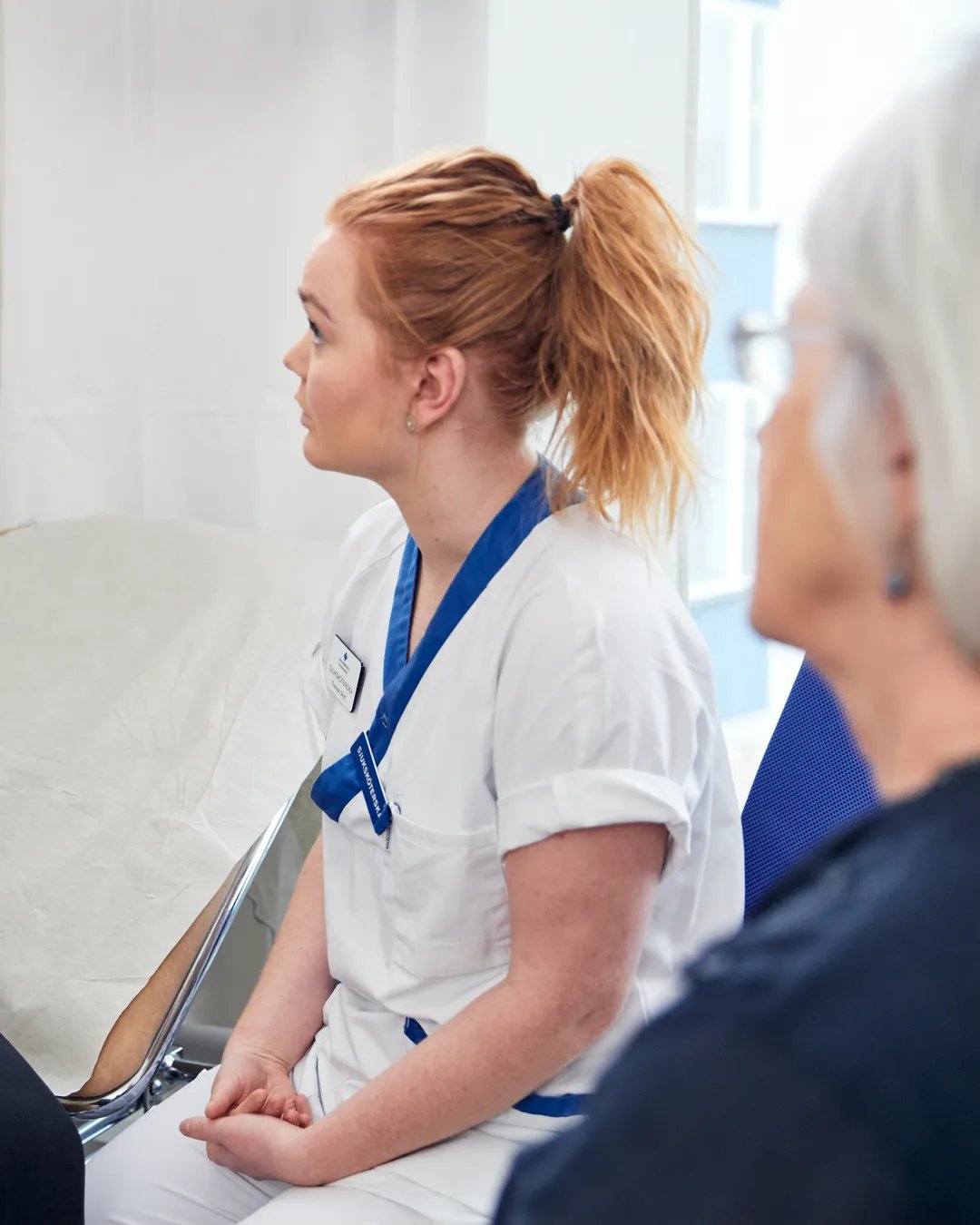 En sjuksköterska pratar med en patient på ett sjukhus.