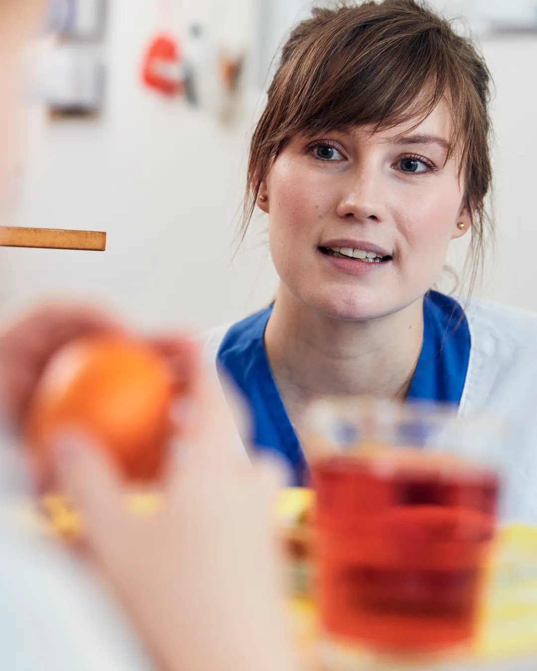 En dietist pratar med en patient som äter en apelsin och dricker saft.