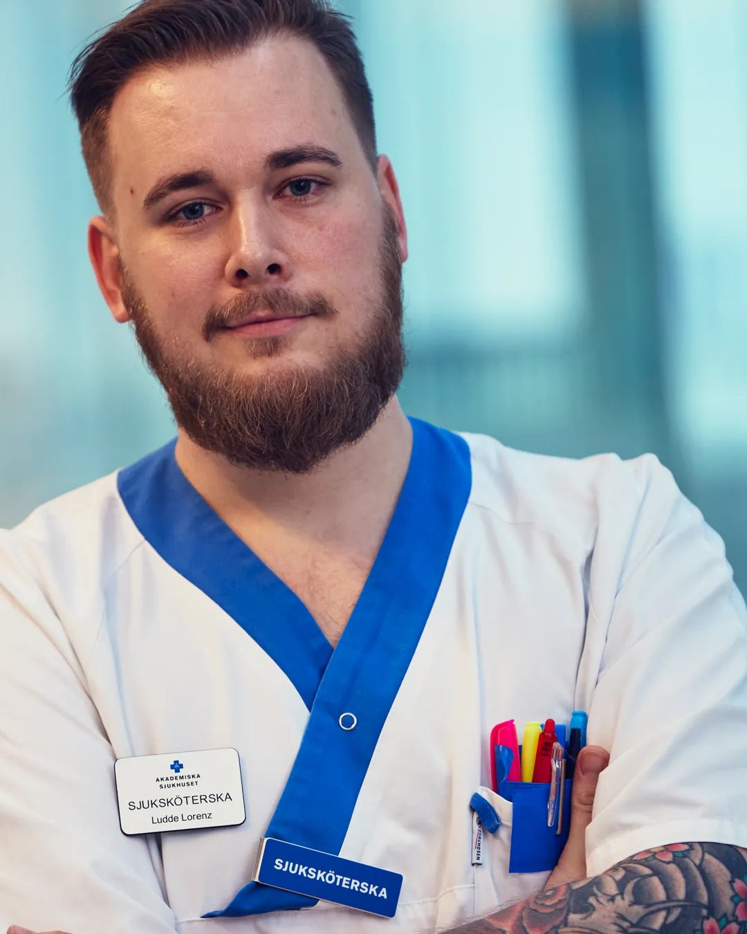 En sjuksköterska som korsar armarna och tittar mot kameran.