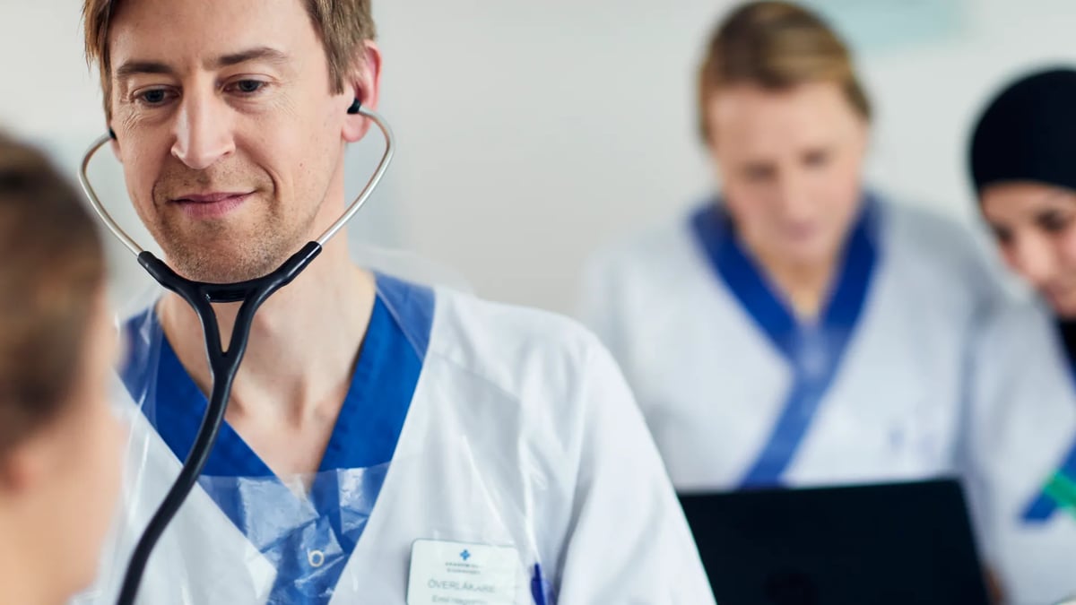 En man med stetoskop står framför en bärbar dator.