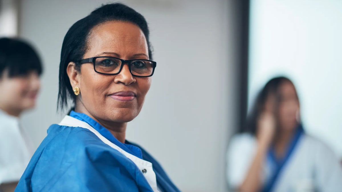 En kvinna med glasögon och blå jacka.