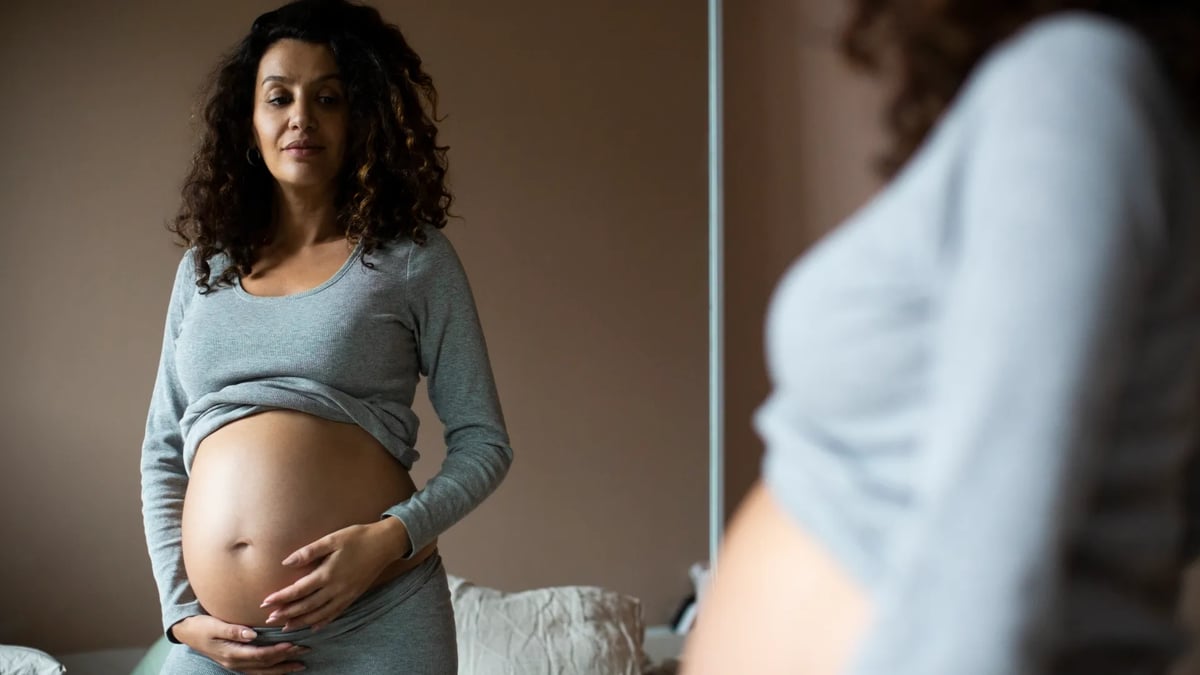 En gravid kvinna står framför en spegel.