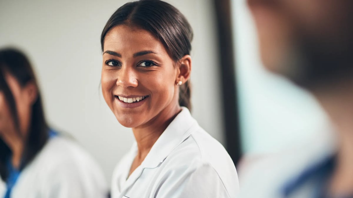 En kvinnlig vårdpersonal ler mot kameran.