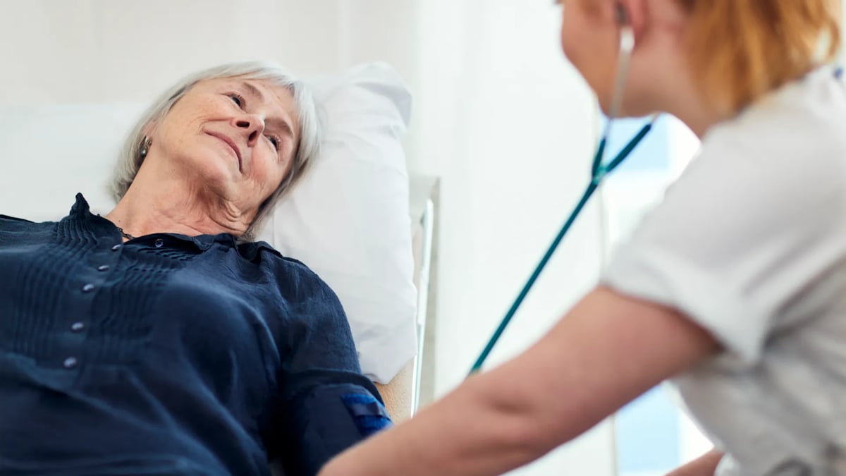 En kvinna i en sjukhussäng med ett stetoskop.