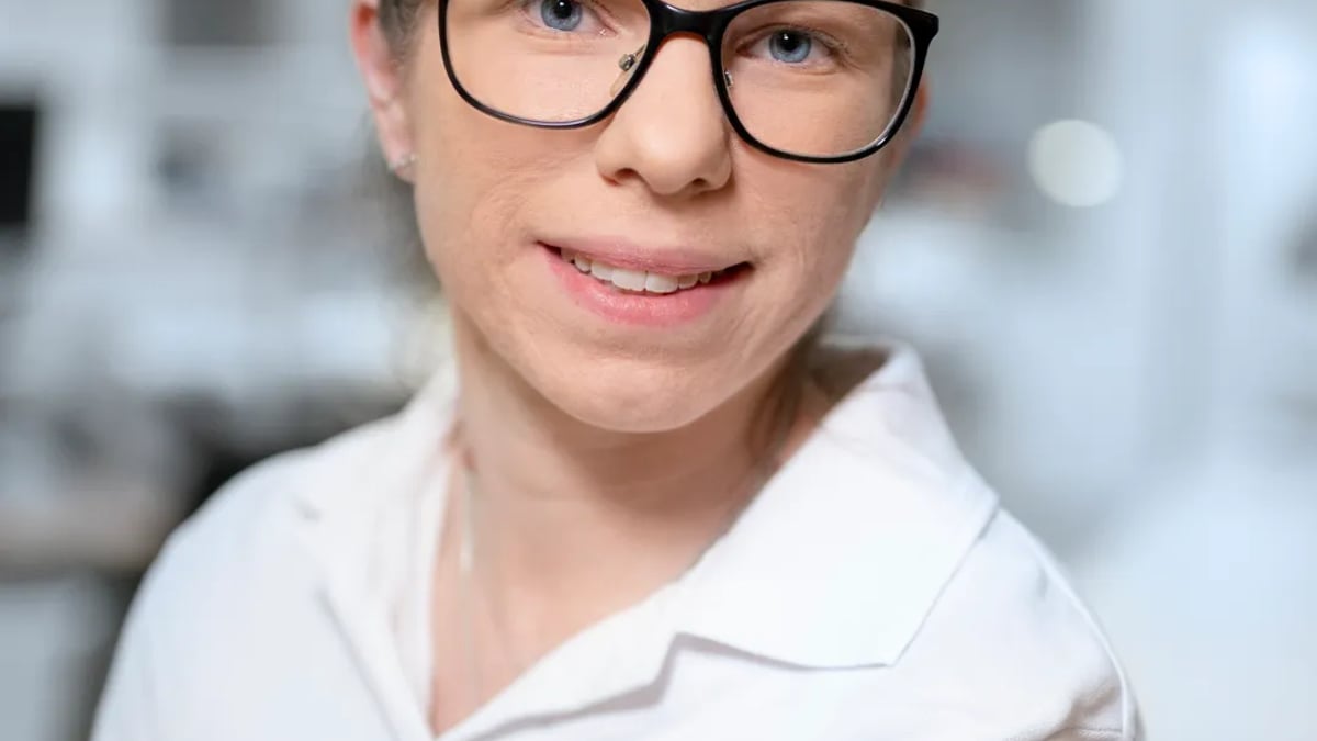 A woman wearing glasses and a white shirt.