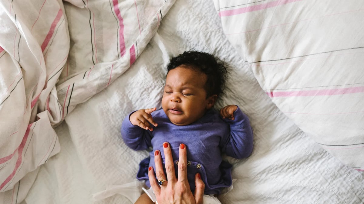 En kvinna med en bebis på en säng.