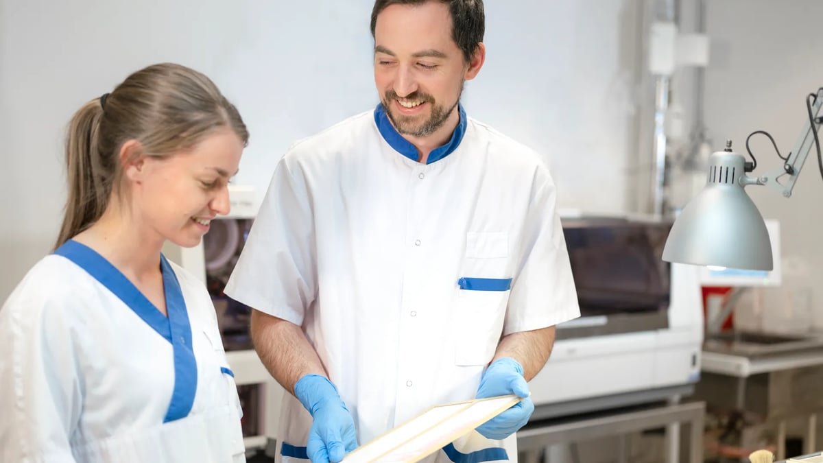 En man och en kvinna i vita arbetskläder pratar med varandra.