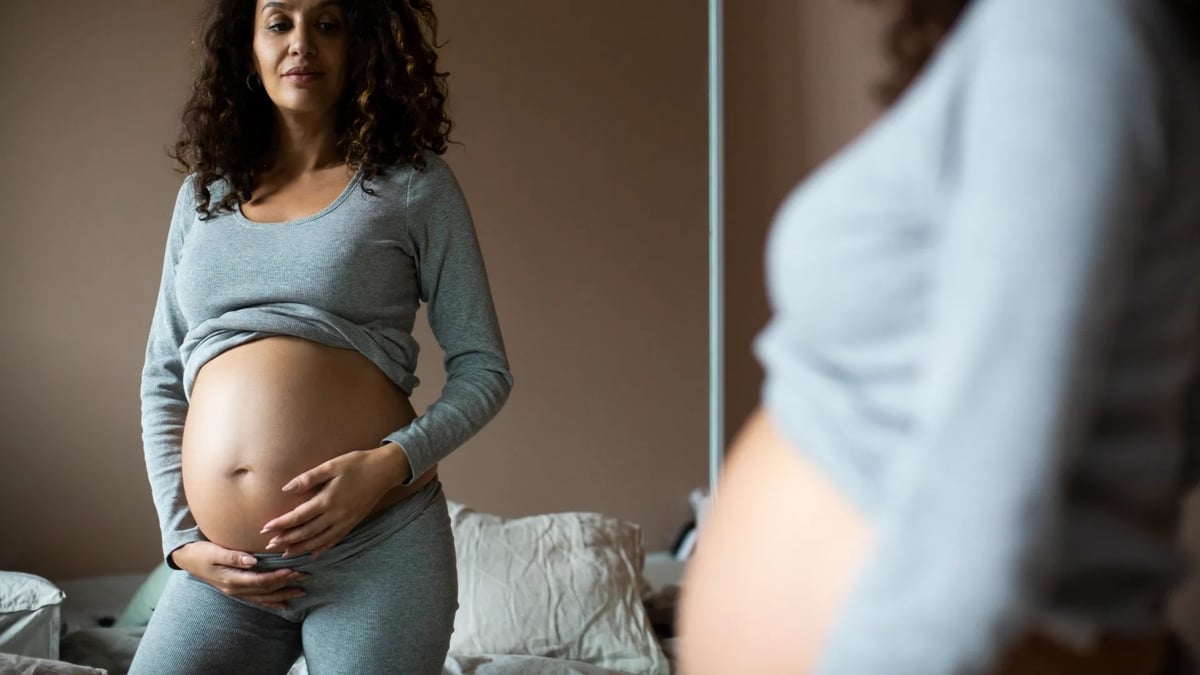 En gravid kvinna står framför en spegel.