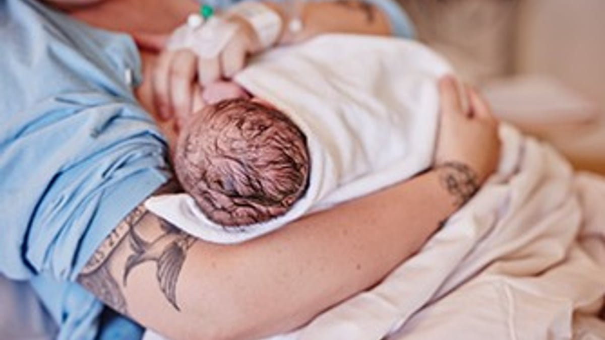 En kvinna håller en baby insvept i en filt.