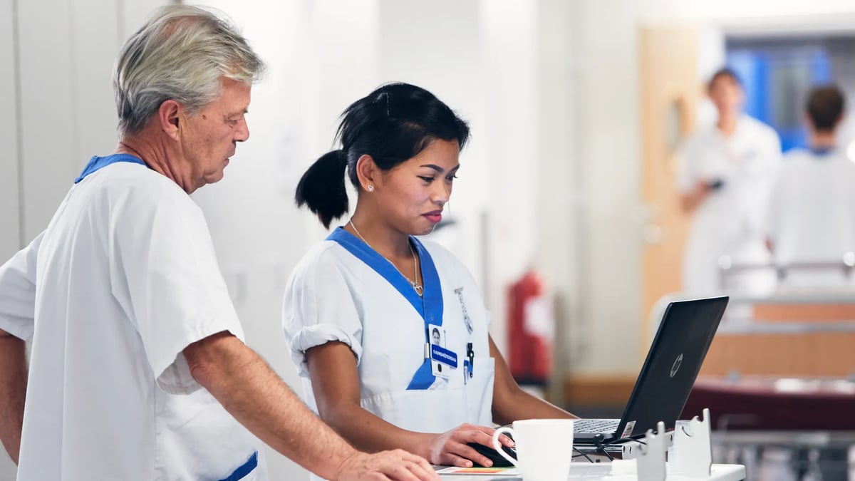 En man och en kvinna står framför en bärbar dator.