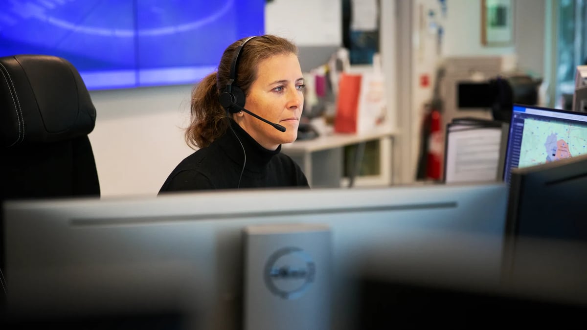 En kvinna med headset sitter framför en dator.