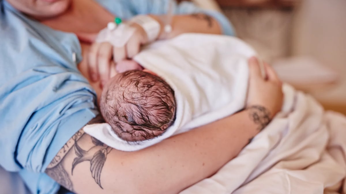 En kvinna håller en baby insvept i en filt.