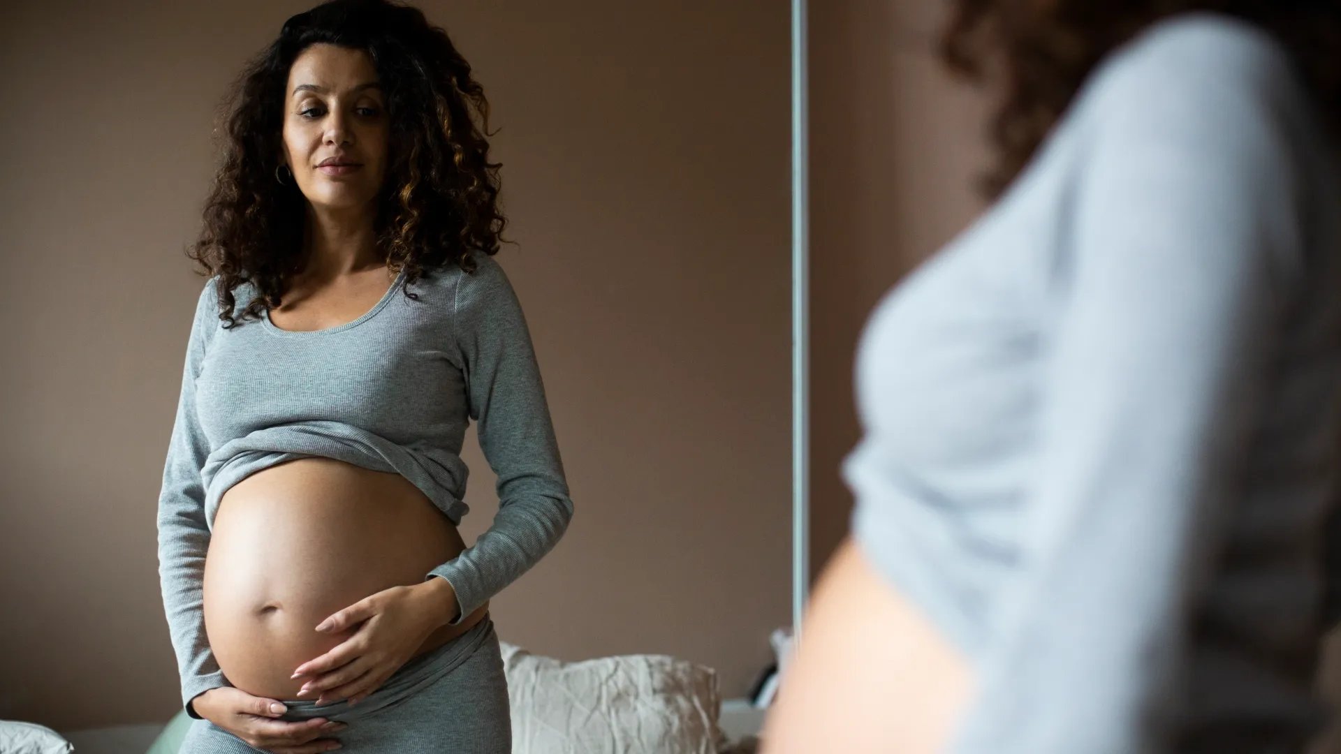 En gravid kvinna står framför en spegel.