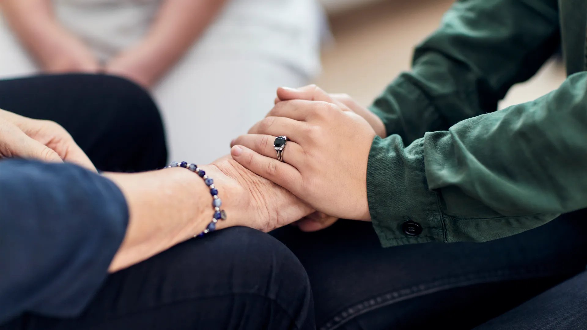 Några personer sitter ner och håller varandra i handen.
