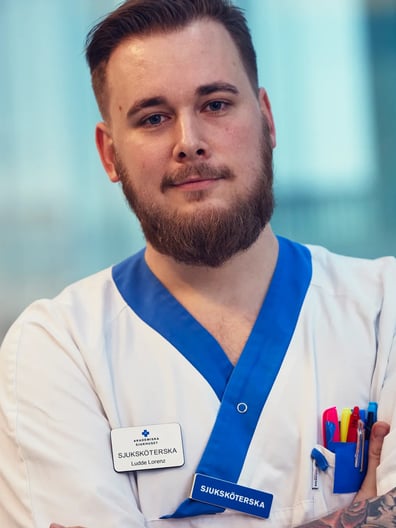 En man med skägg och tatueringar som bär sjukhusuniform.