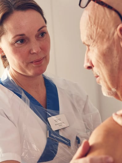 En sjuksköterska som en pratar med en patient.