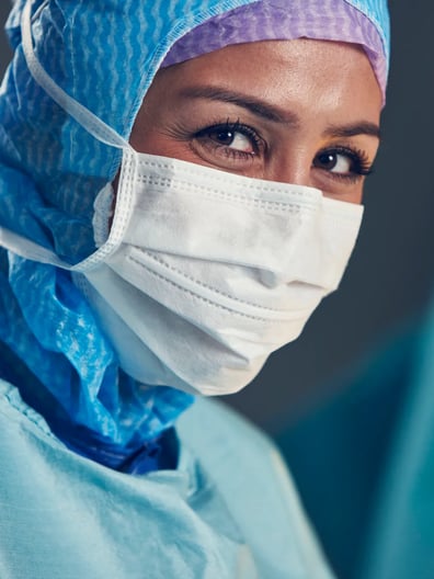 En kvinna iförd kirurgmask och operationskläder.