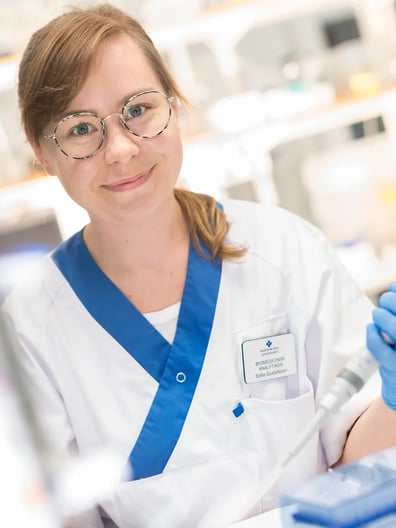 En kvinna i labbrock håller i ett rör.