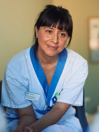 En kvinna i sjukhusuniform sitter i ett sjukhusrum.