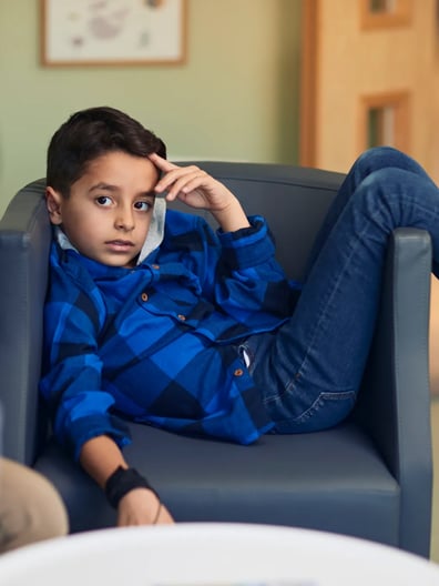 En ung pojke som sitter i en fåtölj och lyssnar på en psykolog.