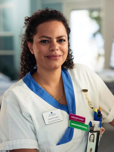 En kvinnlig vårdpersonal ler mot kameran.