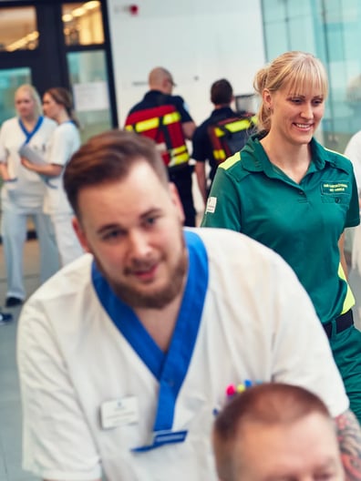 En patient blir skjutsad i rullstol i en sjukhuskorridor.