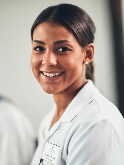 En kvinna i vita kläder ler mot kameran.