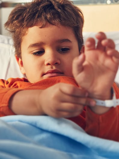 En ung pojke som ligger i en sjukhussäng.