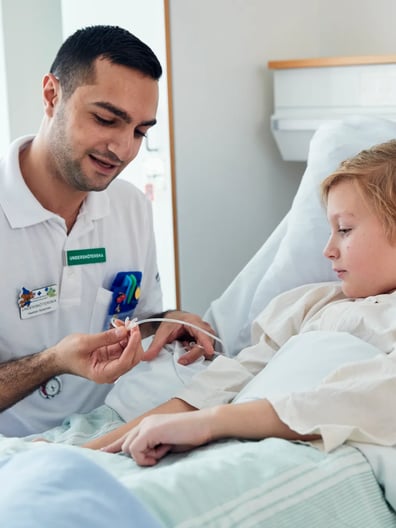 En liten flicka i en sjukhussäng undersöks av en läkare.