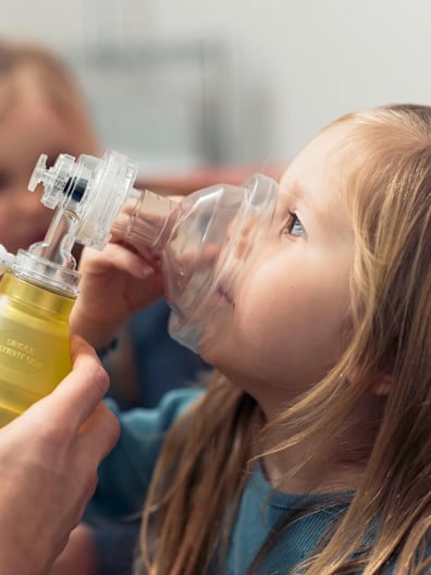 En liten flicka som får hjälp att andas.