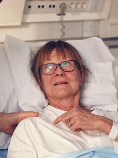 En äldre kvinna i en sjukhussäng undersöks av en läkare.