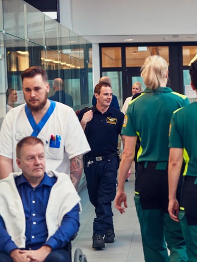 En blandning av patienter och vårdgivare som går i en sjukhuskorridor.