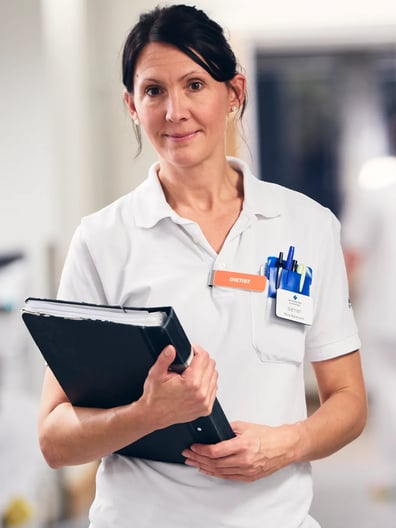 En sjuksköterska håller i en skrivplatta i en sjukhuskorridor.