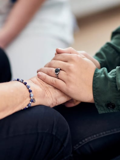 Några personer sitter ner och håller varandra i handen.
