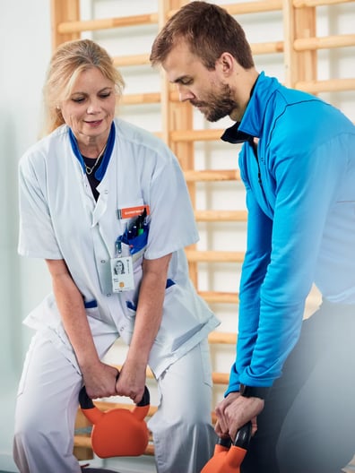 En man och en kvinna i operationskläder lyfter vikter.