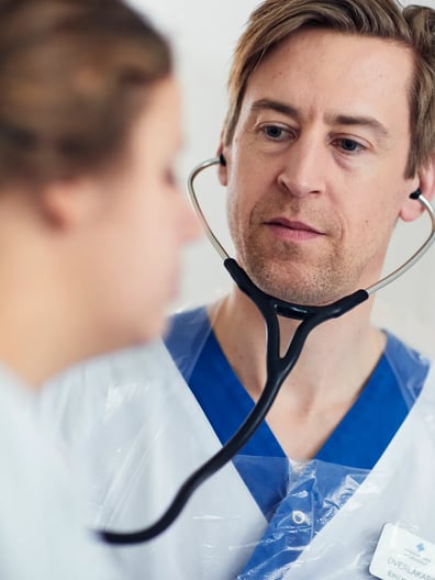 En läkare som lyssnar på en patient med ett stetoskop.