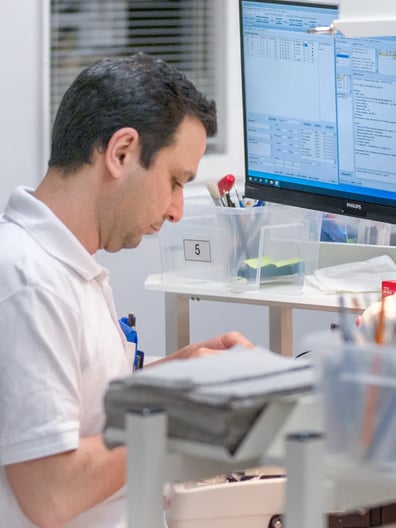 En läkare sitter vid ett skrivbord och gör analytiskt arbete på en dator.