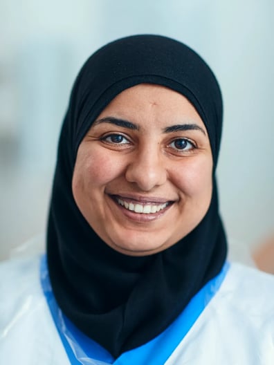 En kvinna i hijab ler mot kameran.