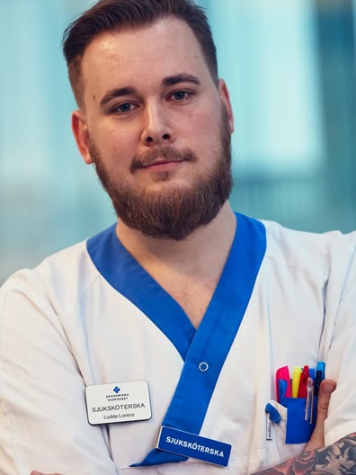 En man med skägg och tatueringar som bär en vit rock.